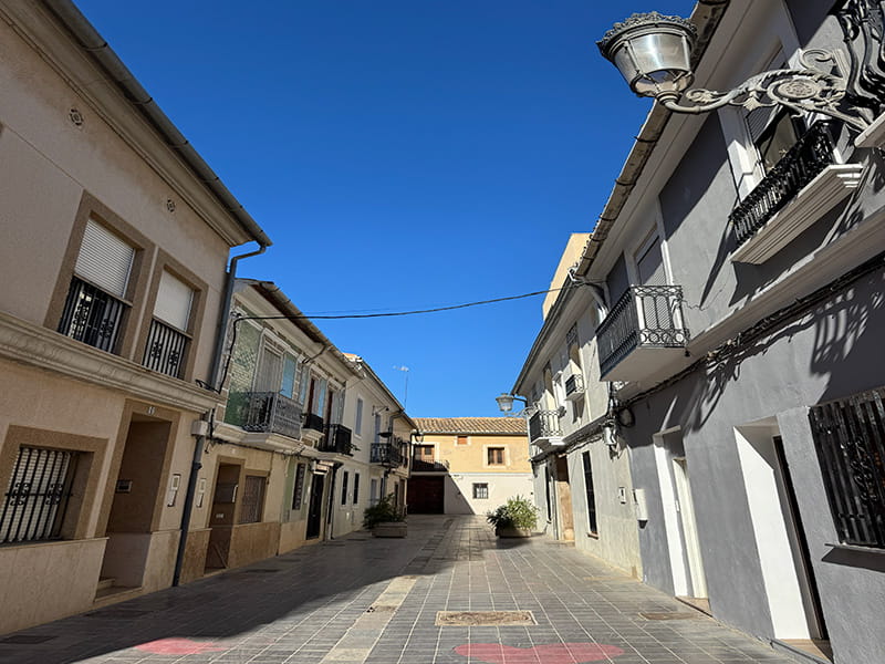 Небольшая площадь и тихая улица с балконами в районе Poblados del Oeste (Валенсия). How-To Spain